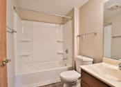 Thumbnail 28 of 33 - A white toilet sits next to a white bathtub in a bathroom.
