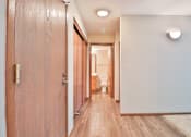 Thumbnail 29 of 33 - A long hallway with wooden floors and doors on either side.