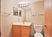 Thumbnail 30 of 33 - A bathroom with a toilet, sink, and mirror.