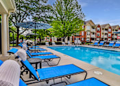 Thumbnail 2 of 93 - A pool area with sun loungers and a building in the background.