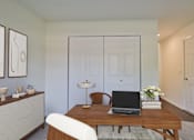 Thumbnail 20 of 93 - A laptop is on a wooden table with a white chair in front of it.