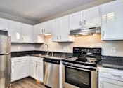 Thumbnail 1 of 37 - A kitchen with white cabinets and a black stove top.