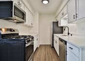Thumbnail 27 of 33 - A kitchen with white cabinets and a black stove top oven.