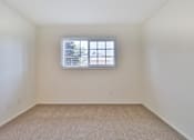 Thumbnail 30 of 33 - A room with a window and carpeted floor.