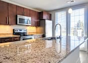 Thumbnail 25 of 31 - A kitchen with granite countertops and stainless steel appliances.