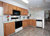Thumbnail 20 of 44 - A kitchen with wooden cabinets and a black microwave above the stove.