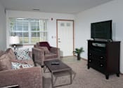 Thumbnail 31 of 44 - A living room with a couch, chair, and television.