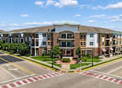 Thumbnail 1 of 12 - A street view of a residential area with apartment buildings and a pedestrian crossing.
