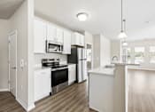 Thumbnail 2 of 12 - A modern kitchen with white cabinets and stainless steel appliances.