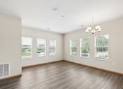 Thumbnail 5 of 12 - A large empty room with wooden floors and a chandelier.