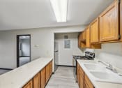 Thumbnail 4 of 44 - an empty kitchen with wood cabinets and white countertops and a sink and a refrigerator