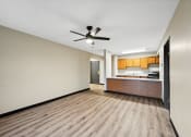 Thumbnail 33 of 44 - a empty living room with a ceiling fan and a kitchen