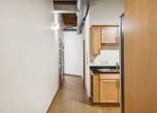 Thumbnail 10 of 35 - a long kitchen with wood floors and white walls and wooden cabinets