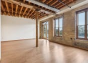 Thumbnail 3 of 35 - an empty room with wood floors and a brick wall and large windows