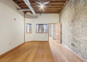 Thumbnail 12 of 35 - an empty living room with a brick wall and wood floors
