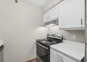 Thumbnail 4 of 21 - an empty kitchen with white cabinets and a black stove and oven