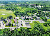 Thumbnail 14 of 52 - An aerial view of a large building complex surrounded by trees and a parking lot.