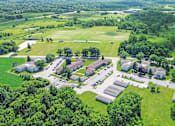 Thumbnail 15 of 52 - An aerial view of a green campus with buildings and a parking lot.
