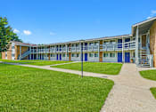 Thumbnail 7 of 52 - A building with blue doors and windows is surrounded by a grassy area.