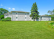 Thumbnail 6 of 52 - A large grassy field in front of a two-story building.