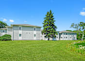 Thumbnail 9 of 52 - A large white house with a grey roof and a green lawn in front.