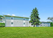 Thumbnail 8 of 52 - A large grey house with a tree in front of it.