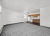 Thumbnail 41 of 52 - A spacious room with a carpeted floor and a kitchen area in the background.