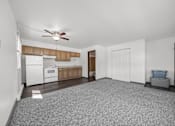 Thumbnail 37 of 52 - A spacious living room with a ceiling fan and a kitchen area in the background.