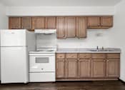 Thumbnail 32 of 52 - A kitchen with white appliances and wooden cabinets.
