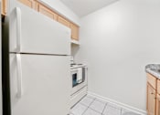 Thumbnail 34 of 52 - A white refrigerator is in a kitchen with a microwave and oven built in.