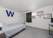 Thumbnail 45 of 52 - A bedroom with a bed, desk, and a wall with a letter W on it.