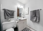 Thumbnail 52 of 52 - A white bathroom with a toilet, sink, and towel racks.