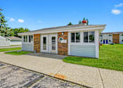 Thumbnail 20 of 52 - A small building with a sign on it is surrounded by a grassy area and a paved walkway.