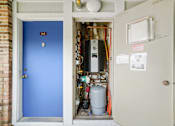 Thumbnail 28 of 52 - A blue door is open to a utility room with a furnace and other equipment.