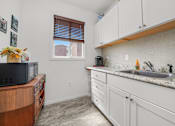 Thumbnail 36 of 52 - A kitchen with white cabinets and a wooden countertop.