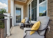 Thumbnail 14 of 31 - A patio with a black chair and a yellow pillow.