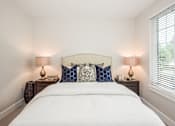 Thumbnail 30 of 31 - A bed with white sheets and a white headboard with blue and white pillows.