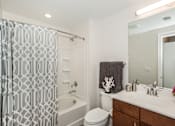 Thumbnail 24 of 31 - A bathroom with a white toilet, a white sink, and a shower curtain.