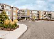 Thumbnail 1 of 31 - A large apartment complex with a circular driveway in front.