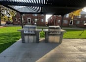 Thumbnail 2 of 27 - Two grills are on a patio in front of a building.
