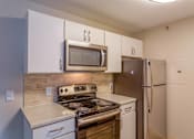 Thumbnail 38 of 43 - A kitchen with a stove, microwave, and refrigerator.