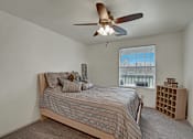 Thumbnail 23 of 48 - A bedroom with a bed, a ceiling fan, and a window.