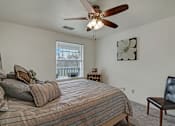 Thumbnail 24 of 48 - A bedroom with a bed, chair, and a ceiling fan.