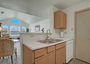 Thumbnail 27 of 48 - A kitchen with a white counter top and wooden cabinets.