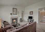 Thumbnail 20 of 48 - A living room with a fireplace and a brown couch.