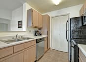 Thumbnail 26 of 48 - A kitchen with a black refrigerator and white countertops.
