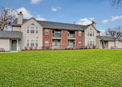 Thumbnail 2 of 48 - A large grassy area in front of a two story apartment building.