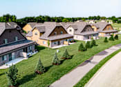 Thumbnail 53 of 60 - A row of houses with green lawns and trees in front.