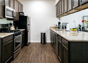 Thumbnail 52 of 60 - A kitchen with dark wood cabinets and a granite countertop.