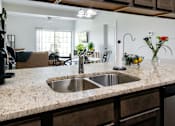 Thumbnail 56 of 60 - A kitchen with a granite countertop and a stainless steel sink.